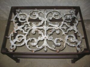 Ferro Designs LLC custom iron coffee table with a dark iron base finish and a white, distressed cast iron top.