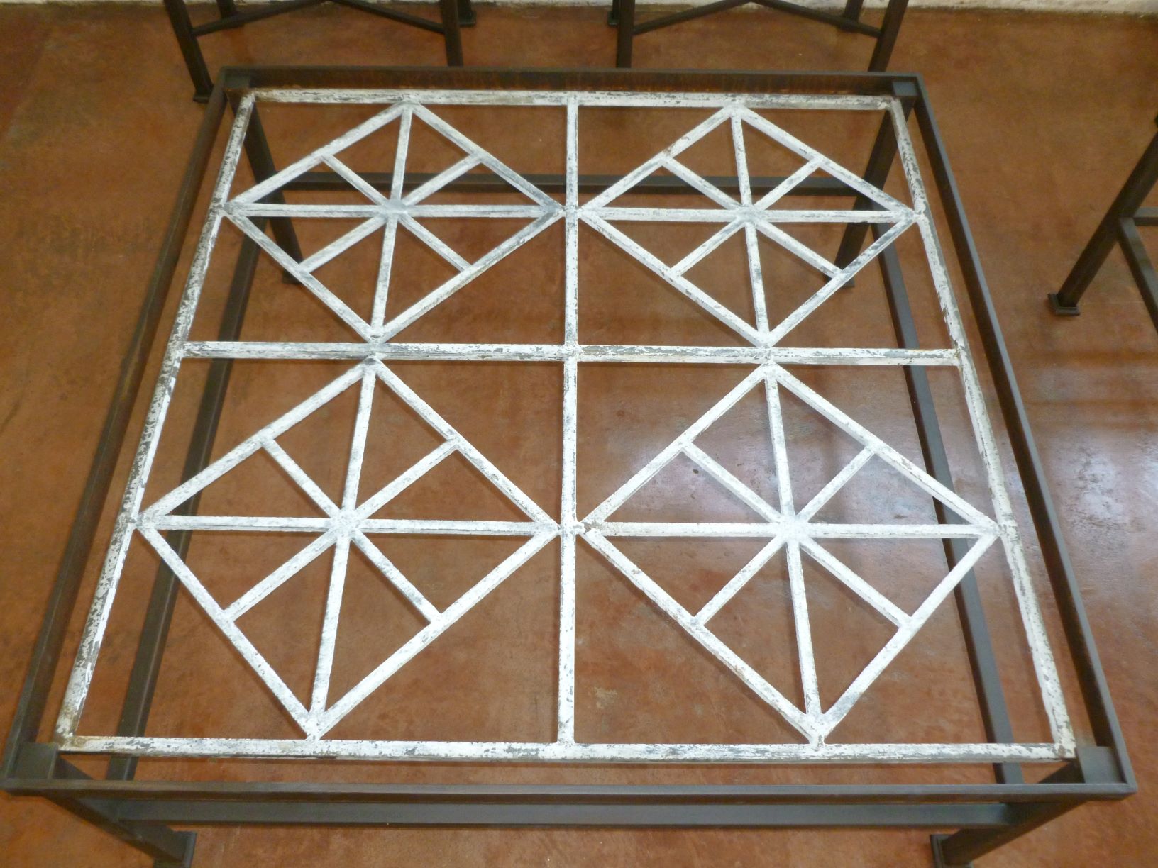 Ferro Designs LLC custom iron coffee table with a dark iron base finish and a white, distressed cast iron top.
