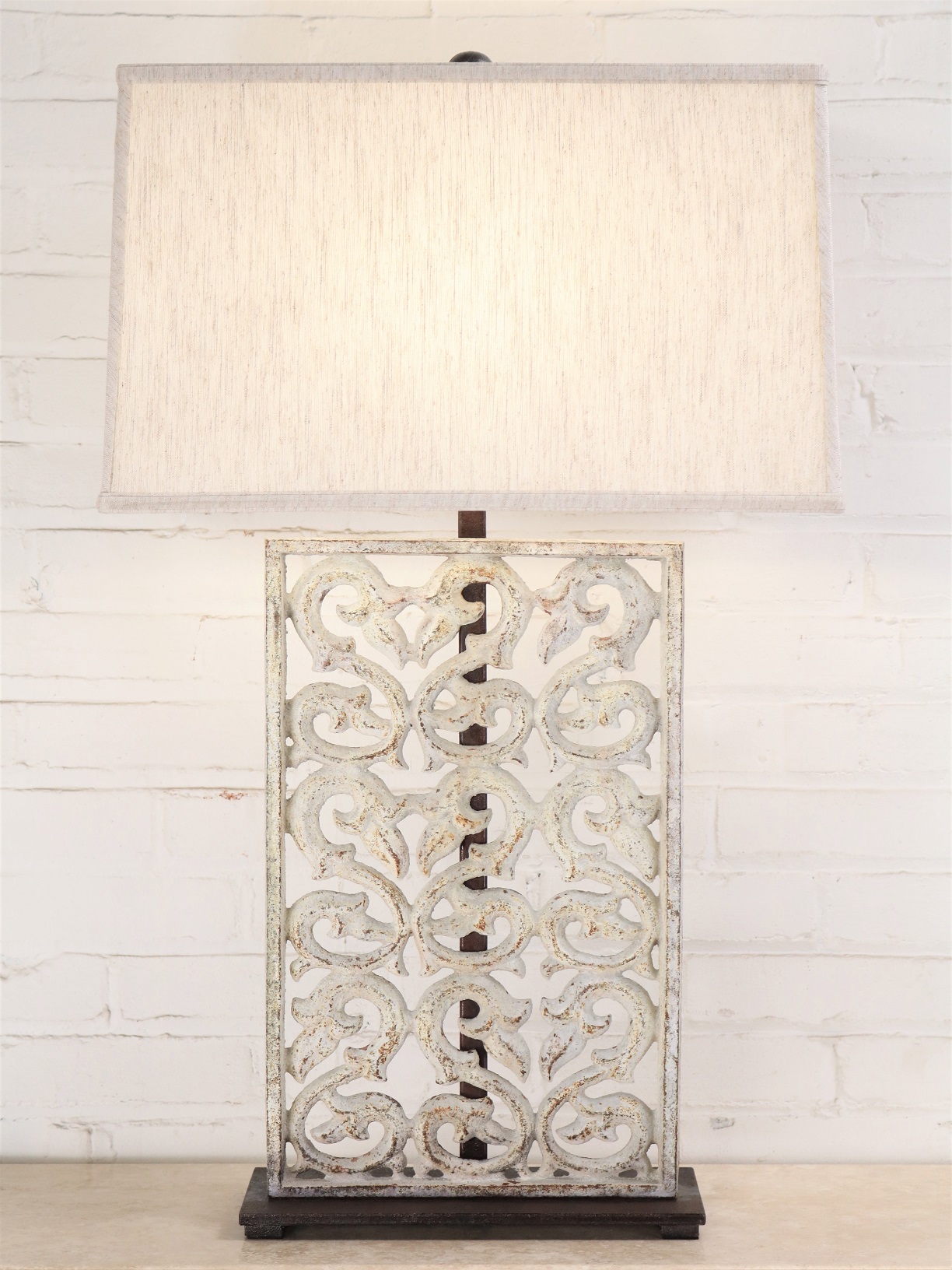 Scrollwork custom iron table lamp with a white distressed finish and a dark iron base. Paired with a 19 inch rectangle linen lamp shade.