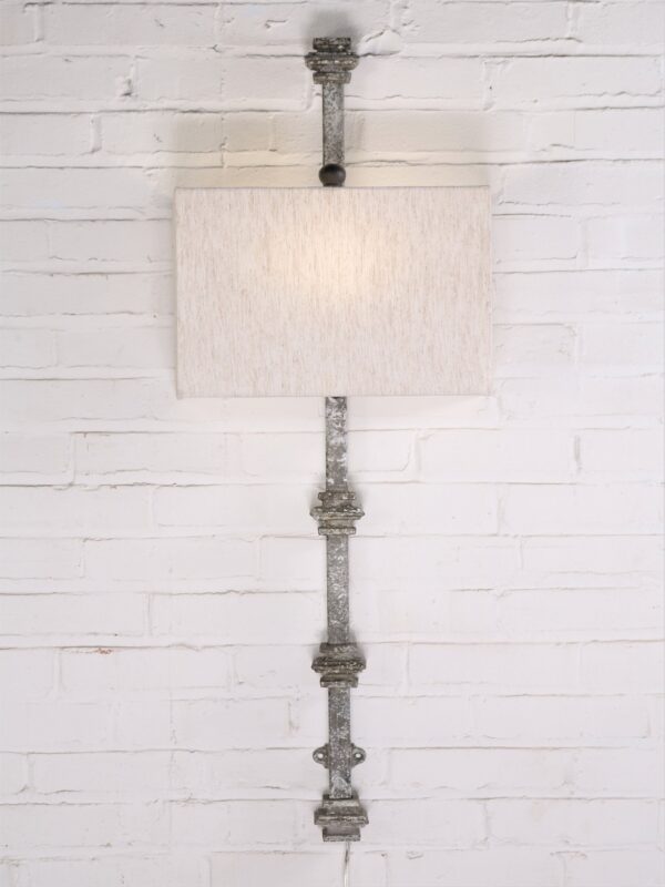 Custom iron wall sconce with a gray, distressed finish and a half rectangle linen lamp shade.
