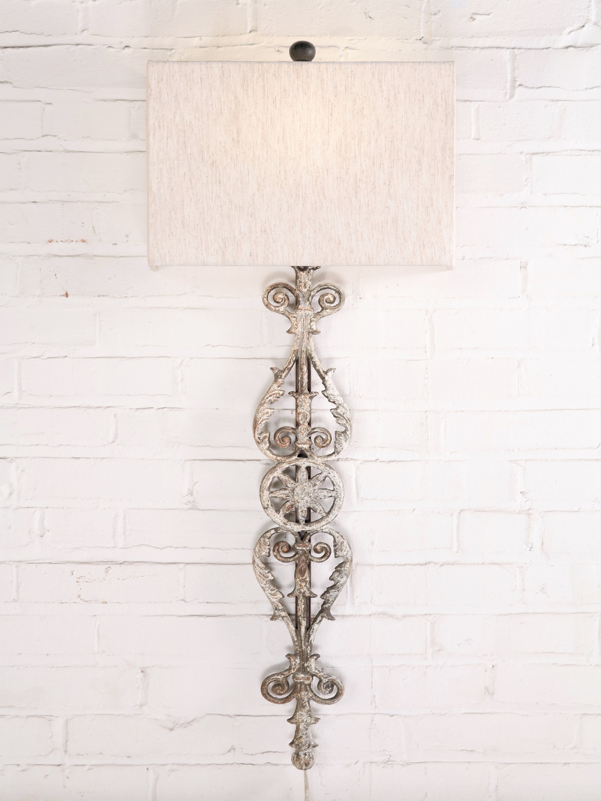 Spanish style custom iron wall sconce with a white, distressed finish. Paired with a half rectangle linen lamp shade.