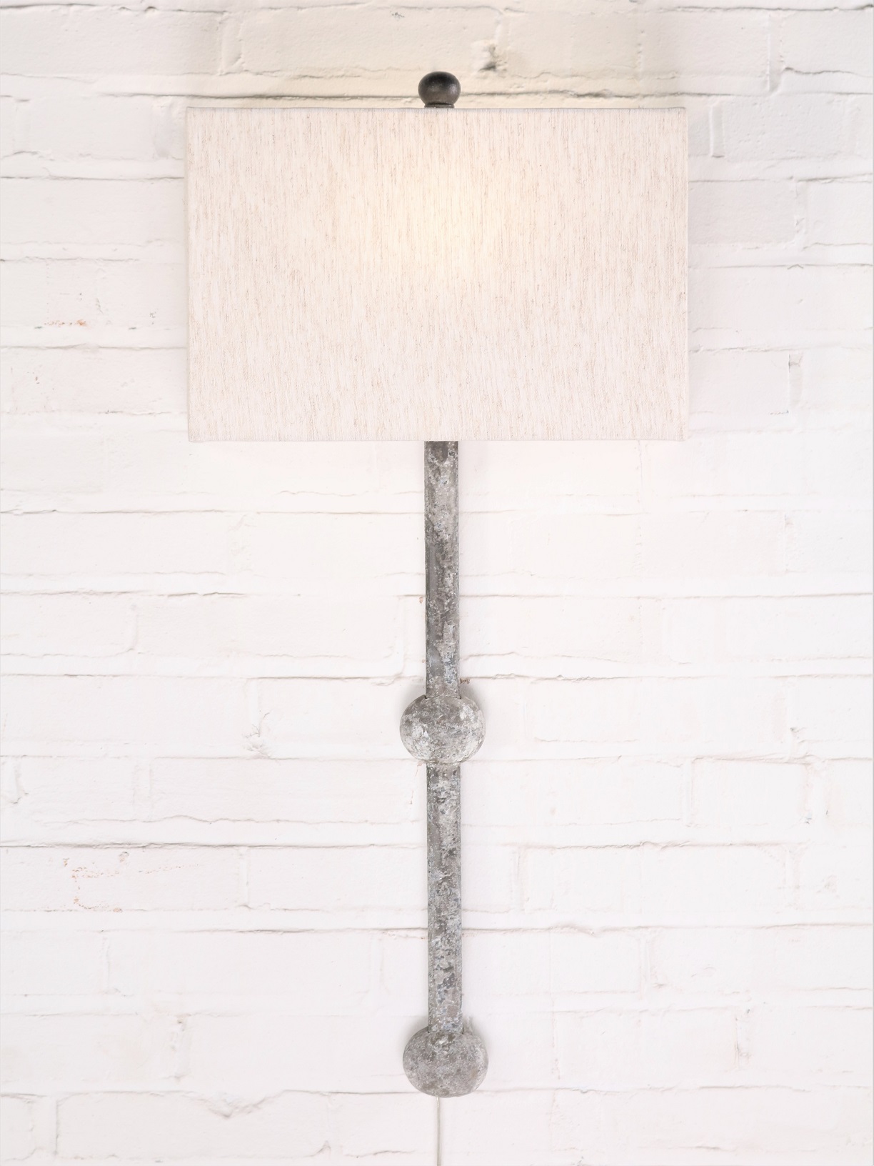 Small sphere custom iron wall sconce with a gray, distressed finish. Paired with a half rectangle linen lamp shade.