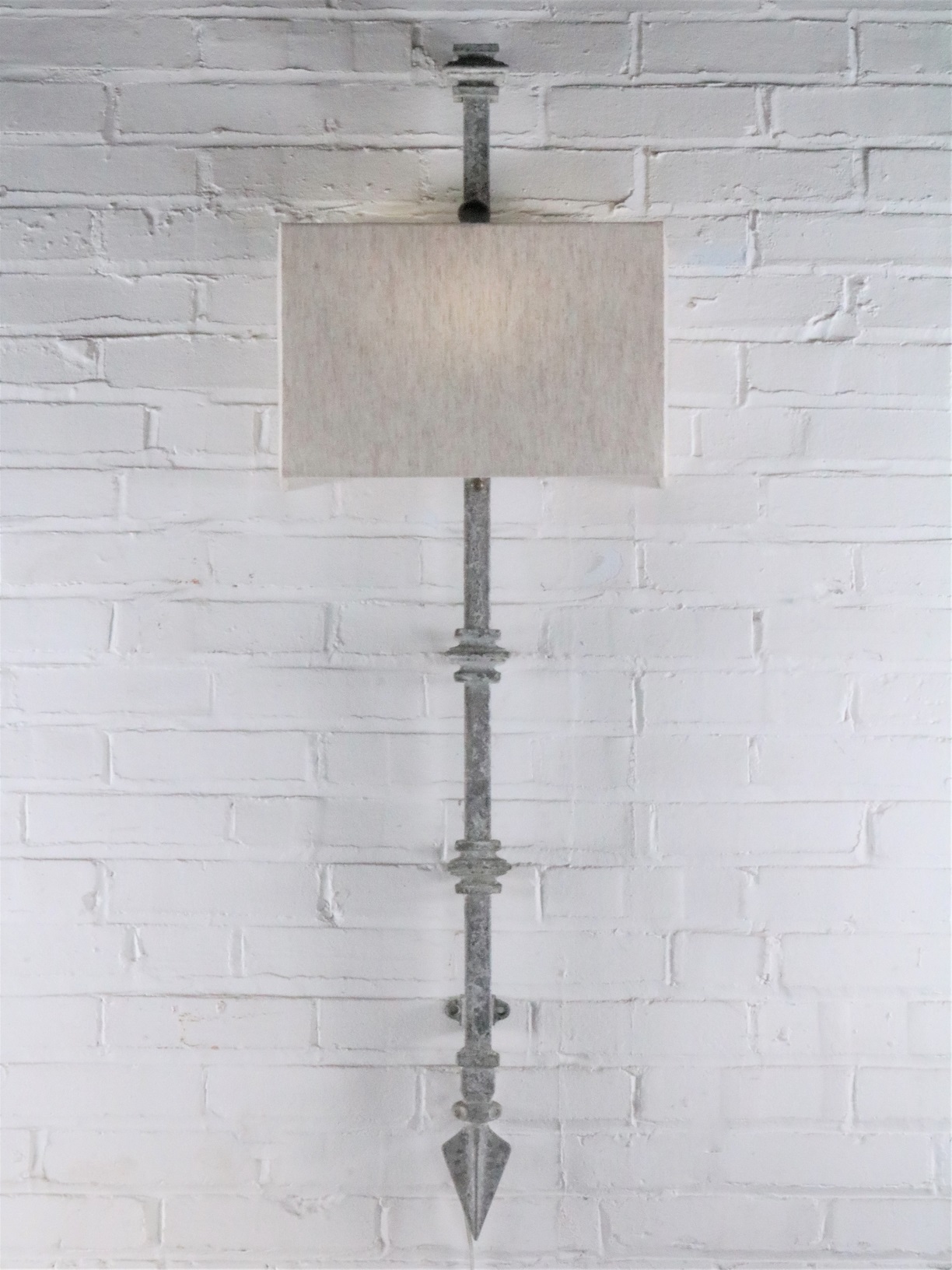 Square collar custom iron wall sconce with a gray, distressed finish. Paired with a half rectangle linen lamp shade.